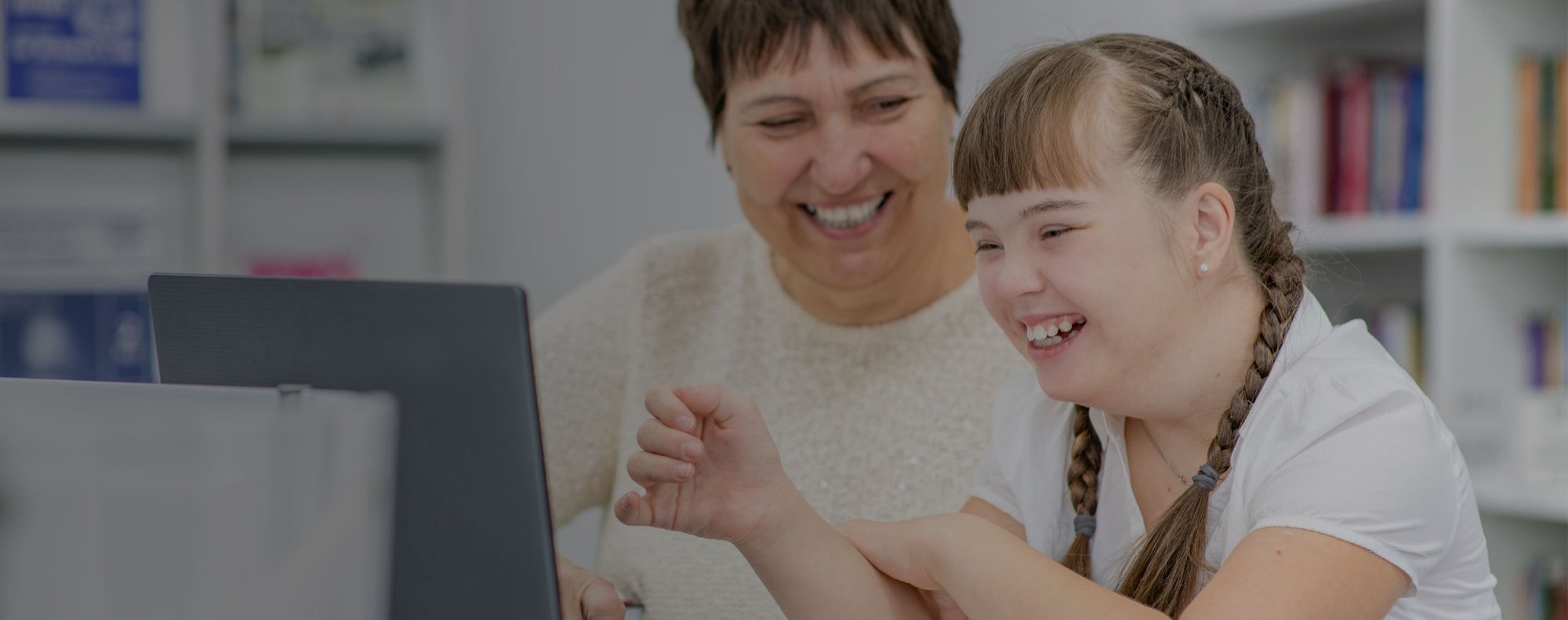 a woman and a girl smiling looking at a computer